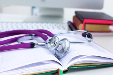 Bir dizüstü bilgisayar arka plan ve kitaplar yatan stetoskop