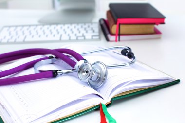 Bir dizüstü bilgisayar arka plan ve kitaplar yatan stetoskop