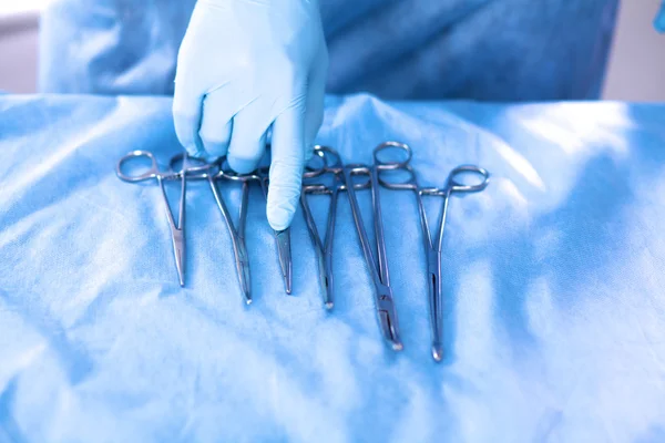 Detalle plano de instrumentos de cirugía esteralizada con una mano agarrando una herramienta — Foto de Stock