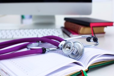 Açık bir kitap bir masada yatan stetoskop