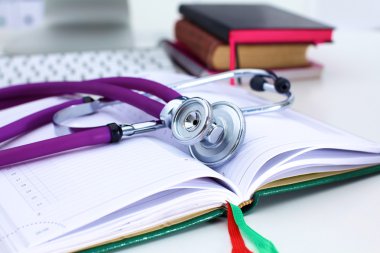 Açık bir kitap bir masada yatan stetoskop