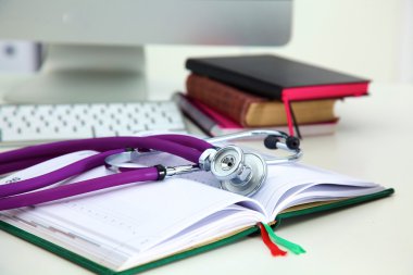Açık bir kitap bir masada yatan stetoskop