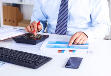 Büyük patron bir hesap makinesi üzerinde hesaplamalar denetler