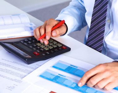 Büyük patron bir hesap makinesi üzerinde hesaplamalar denetler