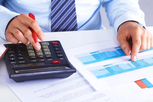 Büyük patron bir hesap makinesi üzerinde hesaplamalar denetler