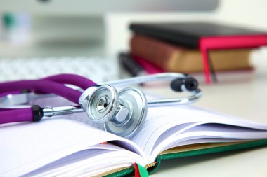 Açık bir kitap bir masada yatan stetoskop