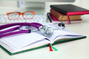 Açık bir kitap bir masada yatan stetoskop