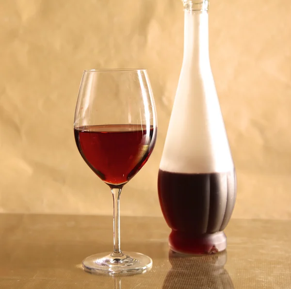 On the table a bottle of wine and a glass of — Stock Photo, Image