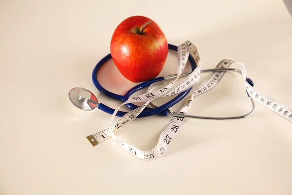 Manzana acostada en una mesa con un estetoscopio y cinta métrica — Foto de Stock