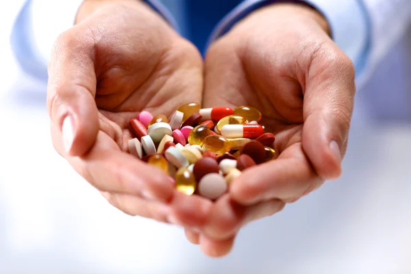 A young doctor holds the patients hand with pills — Stock Photo, Image