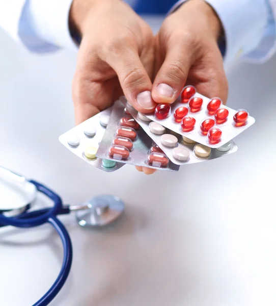 A young doctor holds the patients hand with pills — Stock Photo, Image