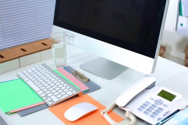 Bilgisayarı ve ahşap masasında akıllı telefonu olan bir ofis.