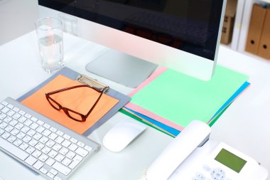 Bilgisayarı ve ahşap masasında akıllı telefonu olan bir ofis.