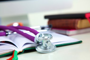 Açık bir kitap bir masada yatan stetoskop