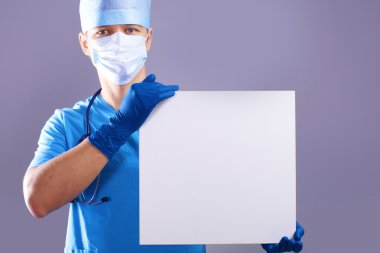 cerrah maskeli bir afişini tutar