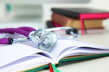 Açık bir kitap bir masada yatan stetoskop