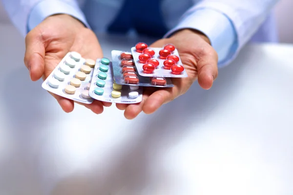 A young doctor holds the patients hand with pills — Stock Photo, Image