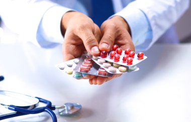 Genç bir doktor hap hastalar eliyle tutan