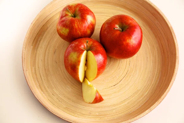 Rote Äpfel auf einem Holzteller auf dem Tisch — Stockfoto