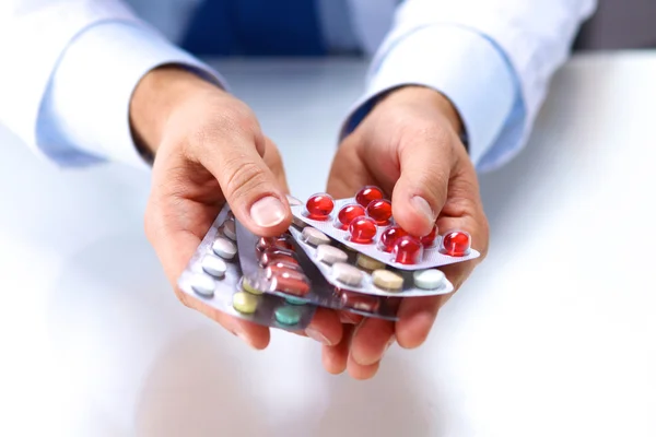 A young doctor holds the patients hand with pills — Stock Photo, Image