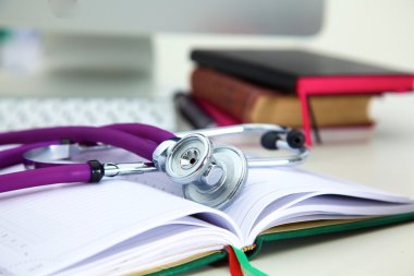 Açık bir kitap bir masanın üzerinde yatan stetoskop