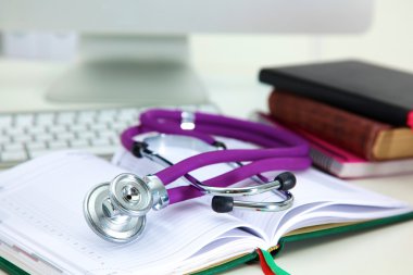 Açık bir kitap bir masanın üzerinde yatan stetoskop