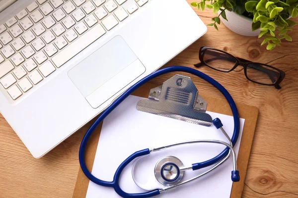 Medical stethoscope near  laptop on  wooden table,  white — Stock Photo, Image