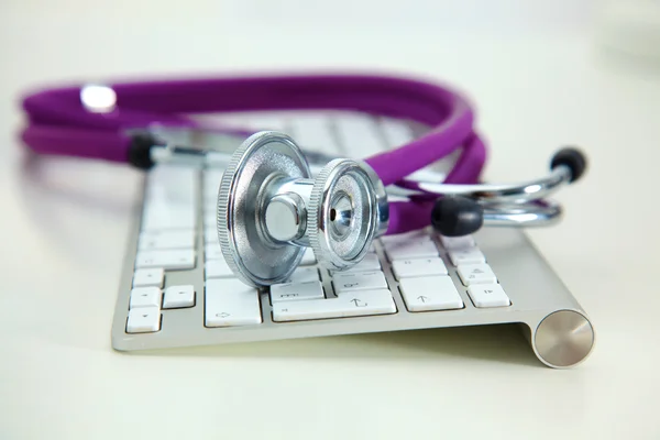 Estetoscopio médico se encuentra en un teclado de computadora — Foto de Stock