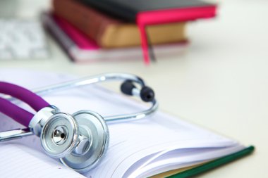 Açık bir kitap bir masanın üzerinde yatan stetoskop