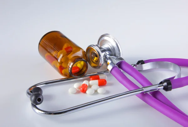 Таблетки, таблетки и стетоскоп на белом фоне — стоковое фото
