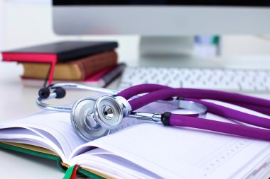 Bir dizüstü bilgisayar arka plan ve kitaplar yatan stetoskop