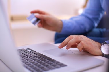 Online alışveriş. Kredi kartı tutan ve dizüstü bilgisayar kullanarak eller