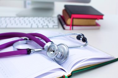 Açık bir kitap bir masanın üzerinde yatan stetoskop