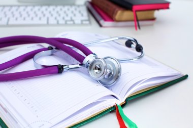 Açık bir kitap bir masanın üzerinde yatan stetoskop