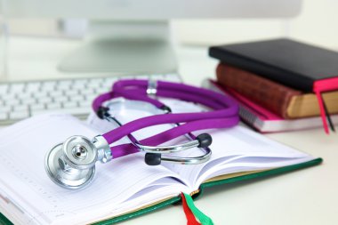 Açık bir kitap bir masanın üzerinde yatan stetoskop