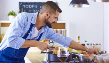 Gülümseyen ve kendinden emin şef büyük mutfakta duruyor.