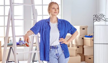 Beyaz tahta bir merdiven üzerinde güzel bir genç kadın. Odayı onarmaya hazırız. Kadın ev işi konsepti