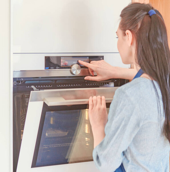 Beautiful woman in the kitchen, waiting with the front of the oven