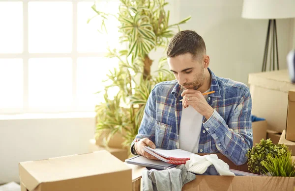 Hombre guapo con cajas en el nuevo apartamento después de mudarse —  Fotos de Stock