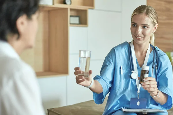 Schöne lächelnde Frau, die der Arzt in einer Flasche Pille dem Patienten anbietet. Ein Allheilmittel oder lebensrettendes Antidepressivum aus einem legalen Geschäft verschreibt Vitaminpflege für einen gesunden Lebensstil — Stockfoto