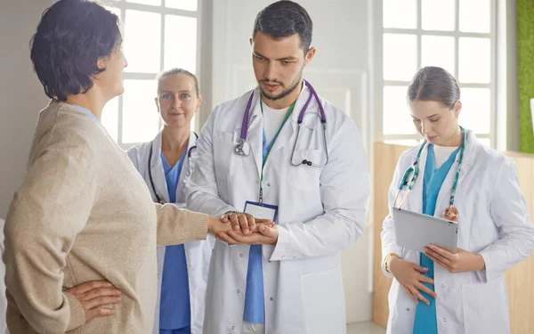 Paziente con un gruppo di medici sullo sfondo — Foto Stock