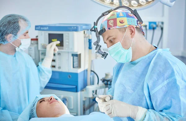 在工作台上, 几位医生围着病人动手术。手术室工作的团队外科医生 — 图库照片