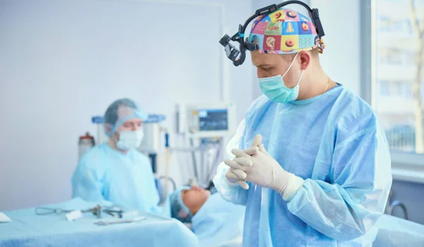 Diversi medici che circondano il paziente sul tavolo operatorio durante il loro lavoro. Chirurghi di squadra al lavoro in sala operatoria — Foto Stock