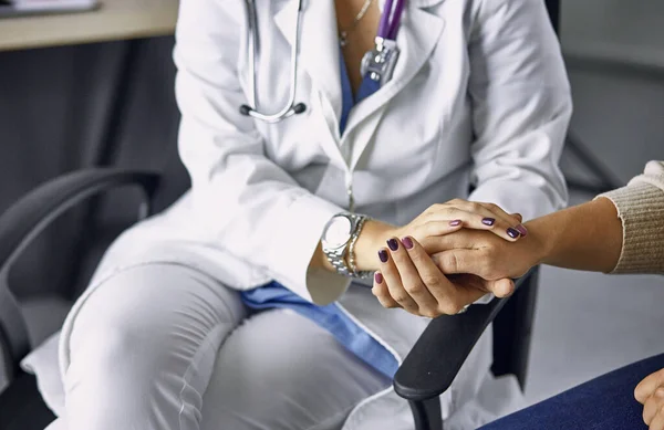 Dokter wanita menenangkan pasien dan berpegangan tangan. — Stok Foto