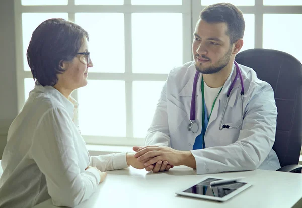 Jovem médico conversando com um paciente no consultório — Fotografia de Stock