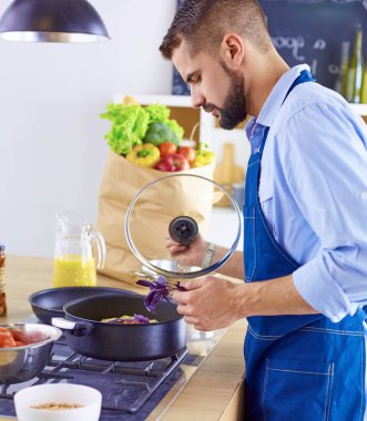 Gülümseyen ve kendinden emin şef büyük mutfakta duruyor.