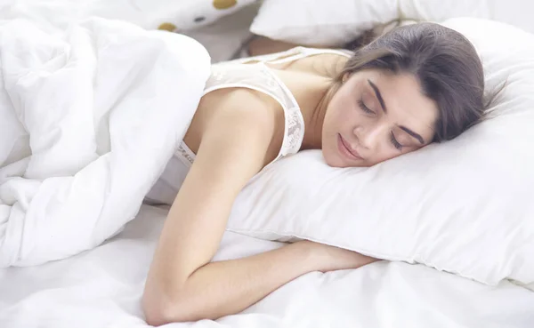 Красива молода жінка в ліжку вранці. Красива модель обличчя виглядає сексуально в камері Стокова Картинка