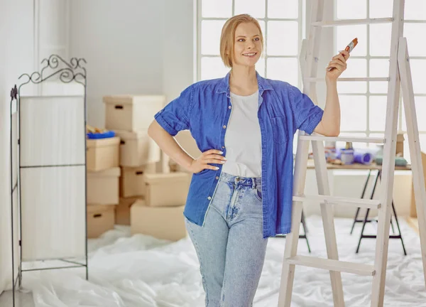 Hermosa joven en una escalera de madera blanca. Listo para reparar la habitación. Concepto de tareas domésticas — Foto de Stock