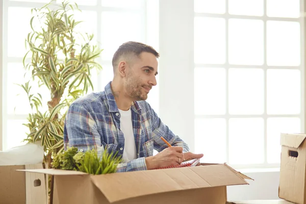 Hombre guapo con cajas en el nuevo apartamento después de mudarse —  Fotos de Stock