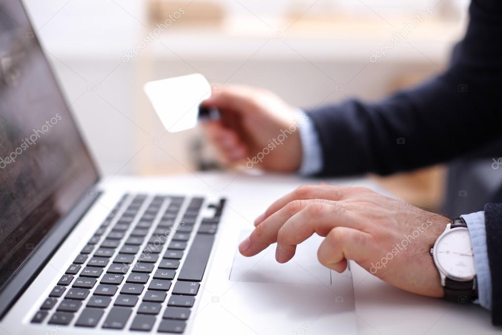 Businessman using his credit card for an online transaction,Businessman using his credit card for an online transaction